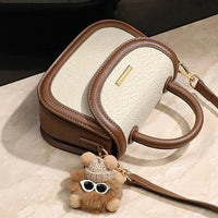 Two-tone cream and brown handbag with handle, gold hardware, and teddy bear keychain