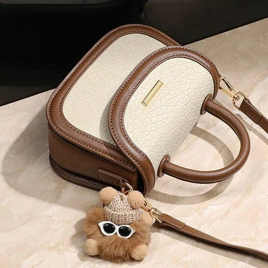 Two-tone cream and brown handbag with handle, gold hardware, and teddy bear keychain