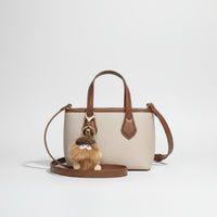 Beige and brown leather crossbody bag with plush pom pom keychain accessory