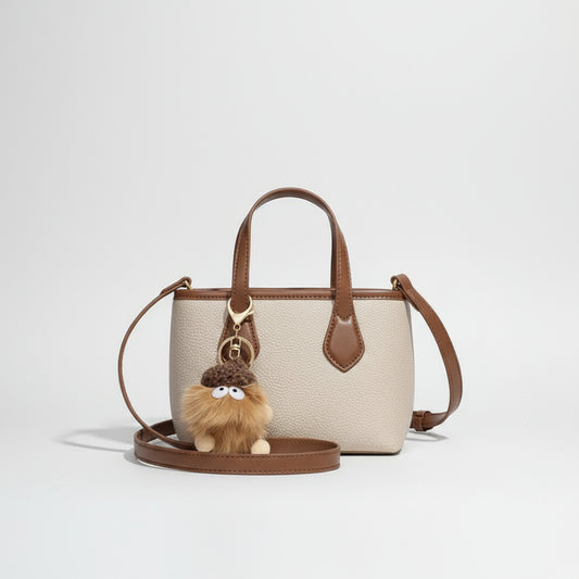 Beige and brown leather crossbody bag with plush pom pom keychain accessory