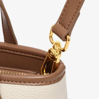 Close-up of beige leather handbag with brown strap and gold hardware detail