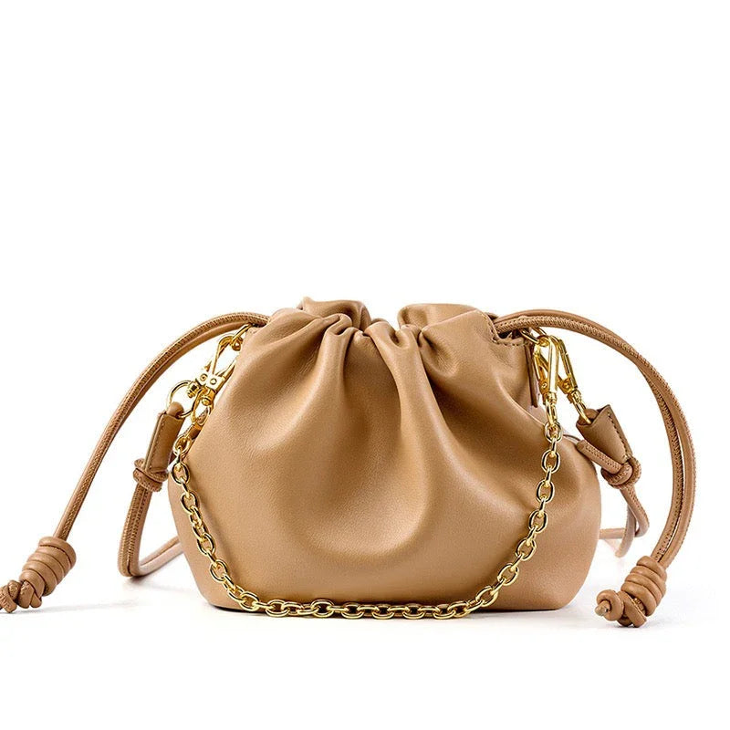 Beige leather drawstring pouch bag with gold chain and knotted straps on white background