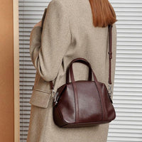 Woman wearing beige coat with brown leather handbag and adjustable strap