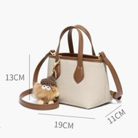 Small beige and brown handbag with shoulder strap, plush keychain, and size dimensions shown.