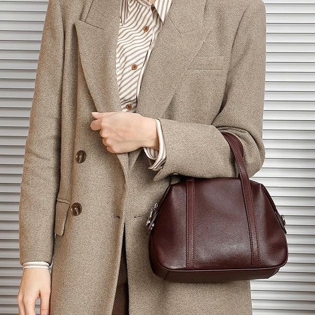 Woman in beige blazer holding burgundy leather handbag, striped shirt, modern fashion