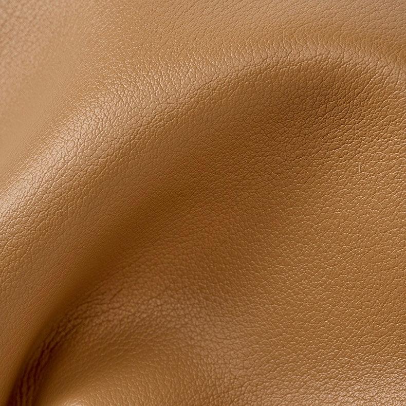 Close-up of tan brown faux leather texture with natural grain and soft folds