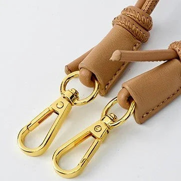 Tan leather strap with gold swivel clasps, close-up on white background