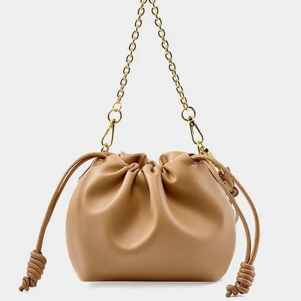 Beige leather drawstring shoulder bag with gold chain strap on white background