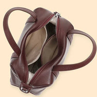 Open burgundy leather handbag with double handles and beige fabric lining