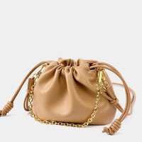 Beige leather drawstring crossbody bag with gold chain strap on white background