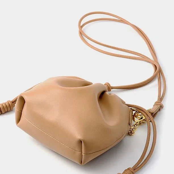 Beige leather crossbody bag with knotted strap and gold chain detail on white background