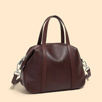 Brown leather handbag with top handles and detachable shoulder strap on beige background