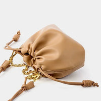 Beige leather drawstring pouch bag with gold chain accents on white background