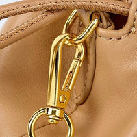 Closeup of gold metal clasp on tan leather handbag