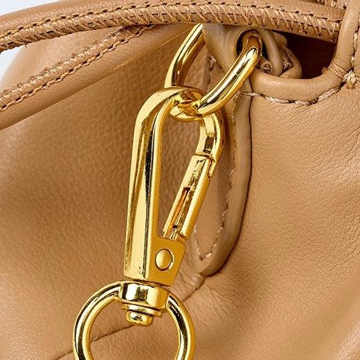 Closeup of gold metal clasp on tan leather handbag