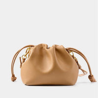 Tan leather drawstring pouch bag with gold hardware on a white background