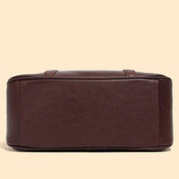 Bottom view of a brown leather handbag on a beige background