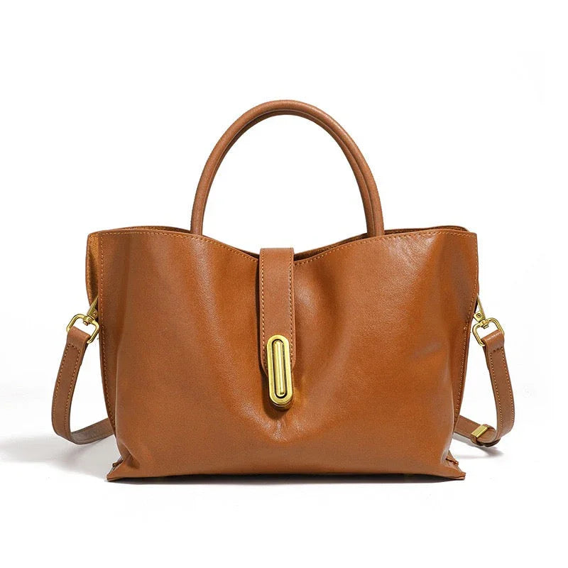 Brown leather handbag with gold hardware, top handle and shoulder strap on white background