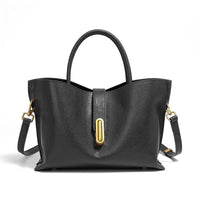 Black leather handbag with gold hardware and top handles on a white background