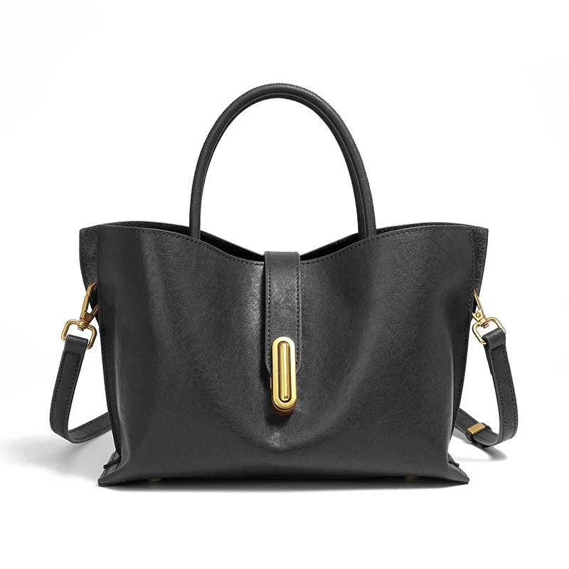 Black leather handbag with gold hardware and top handles on a white background