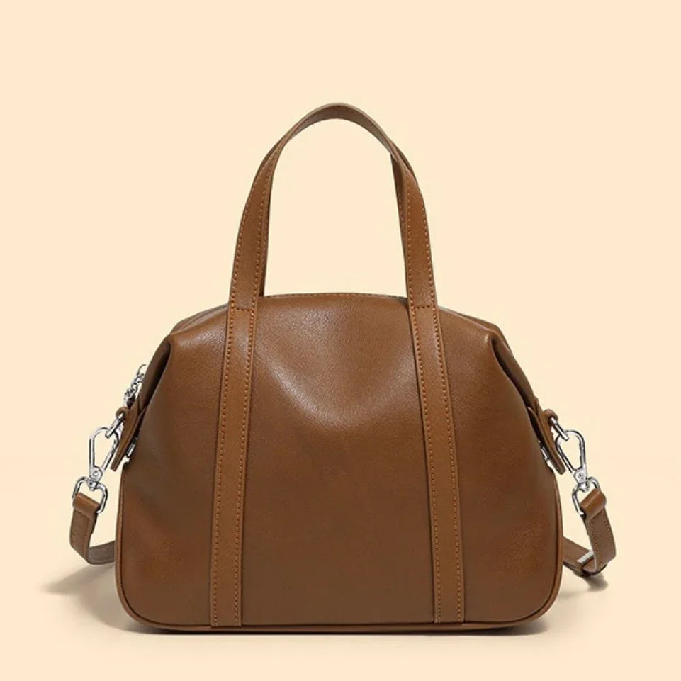 Brown leather handbag with shoulder strap on beige background