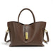 Brown leather tote bag with gold hardware and detachable shoulder strap on white background