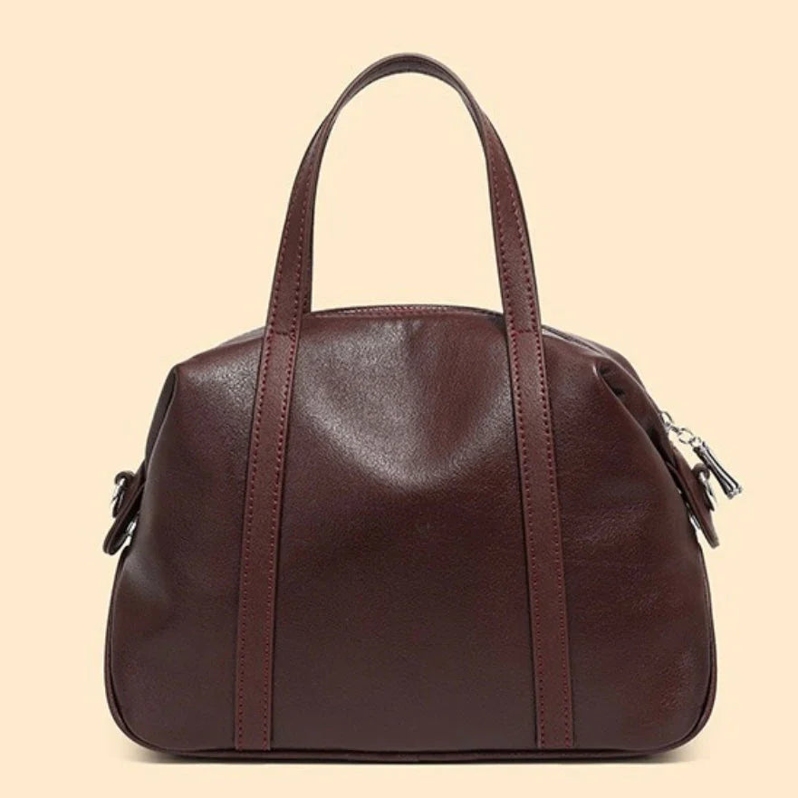 Brown leather handbag with dual handles on beige background