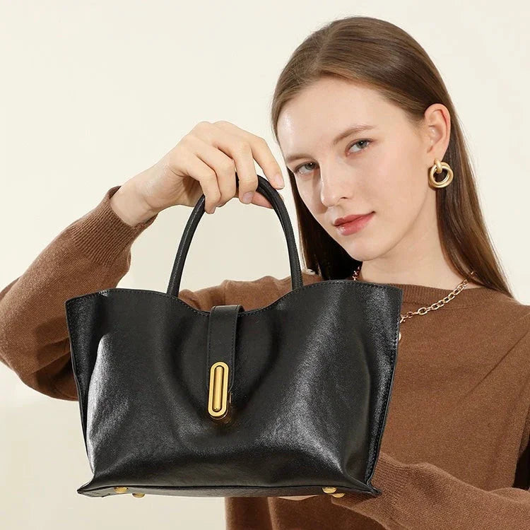 Woman in brown sweater holding black leather handbag with gold hardware