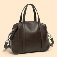 Dark brown leather handbag with top handles and shoulder strap on beige background