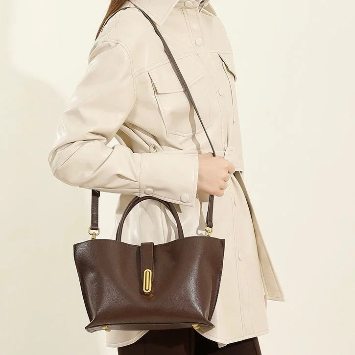 Woman in cream jacket carrying dark brown leather handbag with gold accents