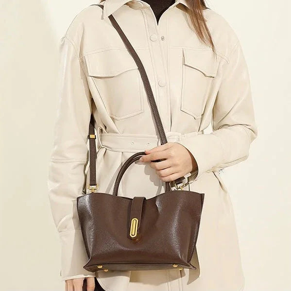 Woman in beige belted shirt dress holding brown leather handbag with gold hardware