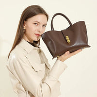 Woman in beige jacket holding elegant brown leather handbag with gold hardware