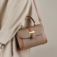 Brown leather shoulder bag with gold hardware on beige coat