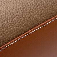 Brown textured leather with white stitching, close-up of luxury leather material