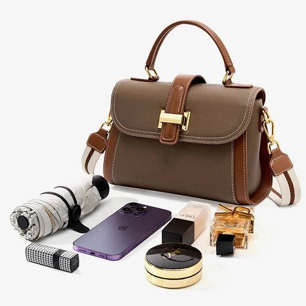 Taupe leather handbag with gold clasp, phone, perfume, makeup, and umbrella on white background