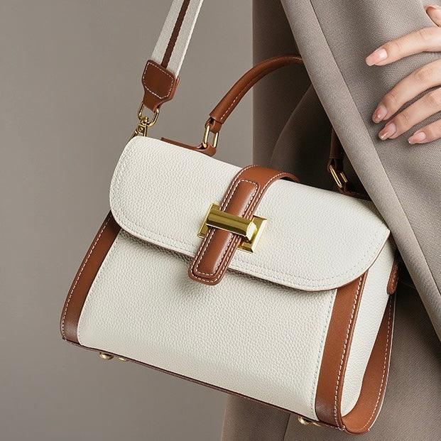 Elegant white and brown leather handbag with gold buckle, held by a woman in a beige coat