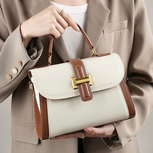 Woman in beige blazer holding elegant cream and brown leather handbag with gold hardware