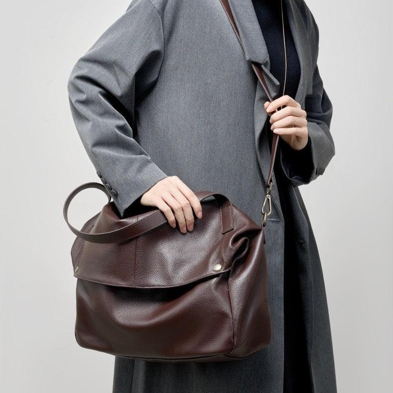 Woman in grey coat holding large brown leather shoulder bag