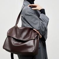 Woman in grey blazer carrying large brown leather shoulder bag