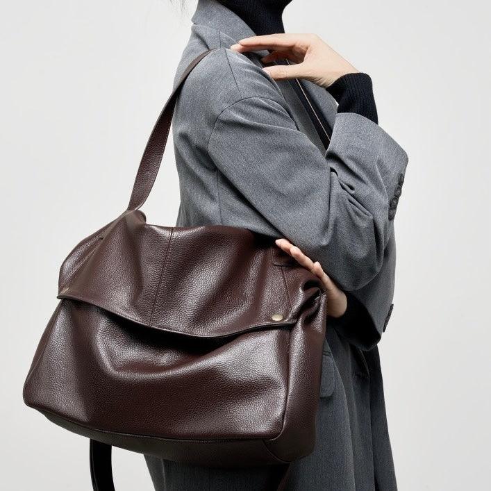 Woman in grey blazer carrying large brown leather shoulder bag