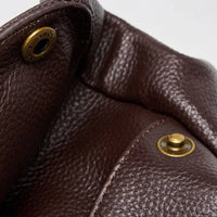 Close-up of brown pebbled leather bag with brass snap button hardware