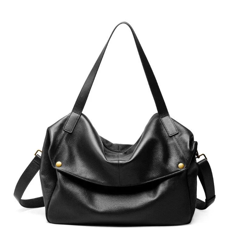 Black leather tote bag with gold accents and shoulder strap on white background