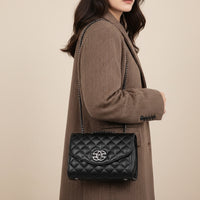 Black quilted leather shoulder bag with chain strap and silver logo on brown herringbone coat