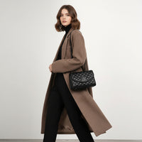 Black quilted leather shoulder bag with chain strap worn over brown herringbone coat