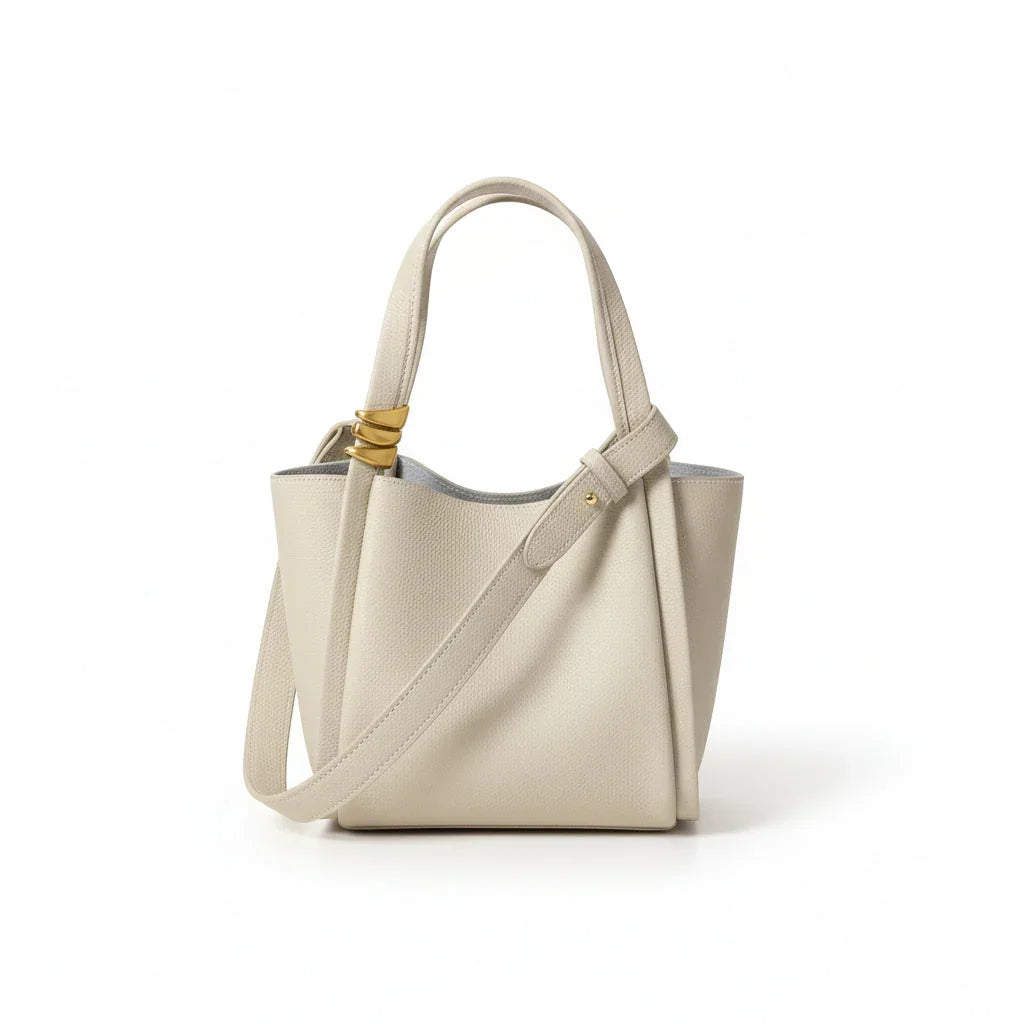 Beige leather tote bag with shoulder strap and gold hardware on white background