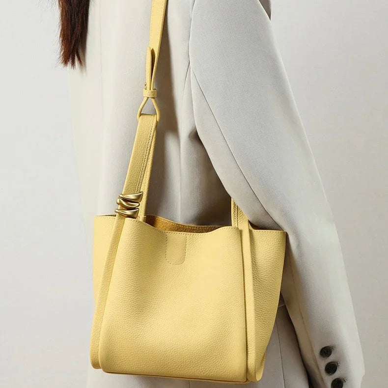 Woman in light blazer carrying a yellow leather shoulder bag with gold rings