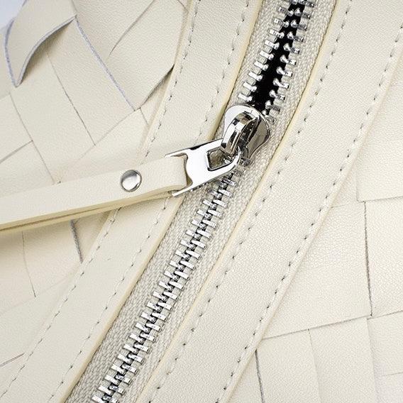 Close-up of cream woven leather handbag with silver zipper detail