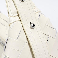 Close-up of cream woven leather sandal strap with silver buckle detail