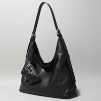 Black leather shoulder bag with small matching pouch on a neutral background