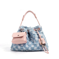 Blue checkered denim bucket bag with pink leather accents and mini pouch on white background